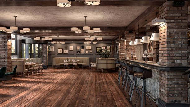 Empty large retro restaurant bar with lounge corners - sofas and tables in front of large windows, decoration and potted plants. A retro restaurant bar with bar stools, drinks, bottles decoration, antique pendant lights on natural hardwood floor and brick pillars.