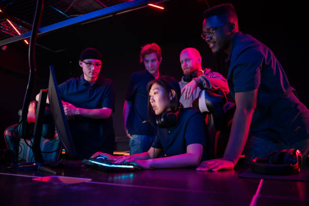 Asian girl playing in a computer club, guys standing behind and prompting Asian girl playing in a computer club, guys standing behind and prompting. esports stock pictures, royalty-free photos & images