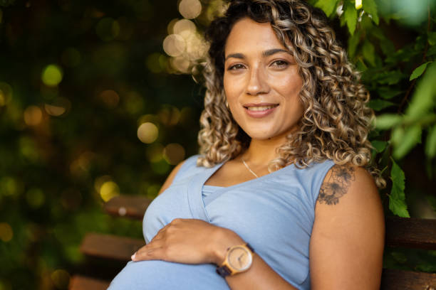 istock Young pregnant woman smiling while sitting on a park bench 1317511174