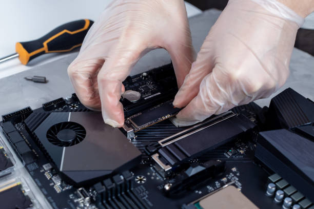 istock Technician is installing new fast high capacity SSD drive on the computer motherboard 1317512583
