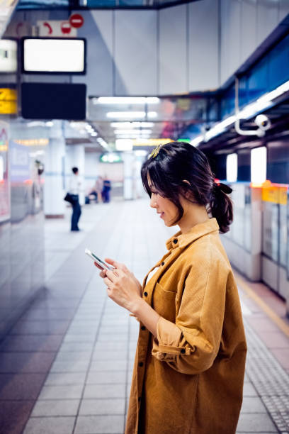 istock Woman using smart phone at subway station 1317514365