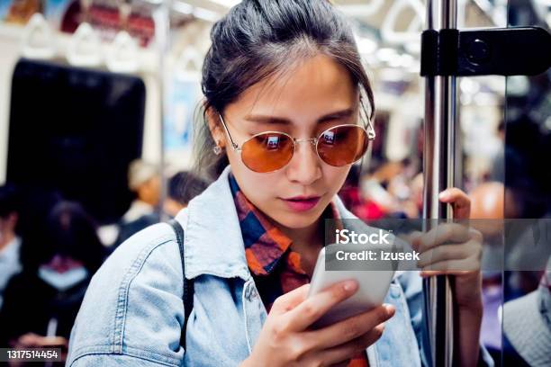 Woman Using Mobile Phone In Subway Train Stock Photo - Download Image Now - Subway Train, Sunglasses, Women