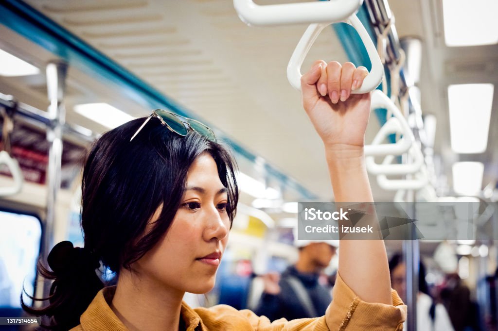 Thoughtful woman traveling in subway train Contemplated female traveling in subway train. Young woman is looking away while holding handle. She is in public transportation. Only Women Stock Photo
