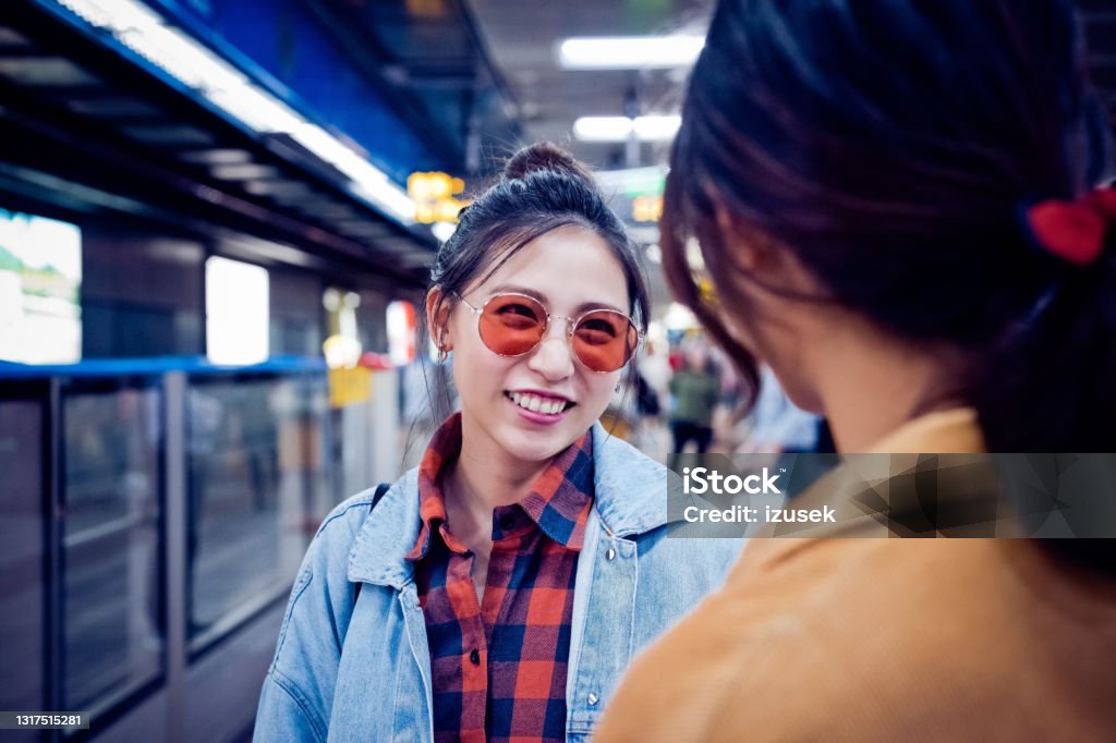 Smiling woman with friend at subway station Smiling young woman with friend. Females are talking while standing at subway station. They are on city break. People Stock Photo