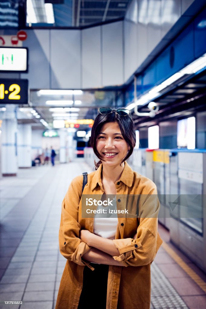 Happy young woman at subway platform Portrait of smiling young woman at platform. Beautiful female is at subway station. She is standing with arms crossed. 20-24 Years Stock Photo