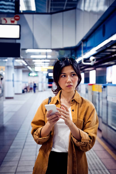istock Female with mobile phone waiting at subway station 1317515938