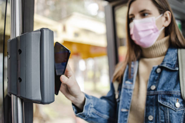 istock Woman with a protective face mask, paying a bus ticket with smart phone 1317516483