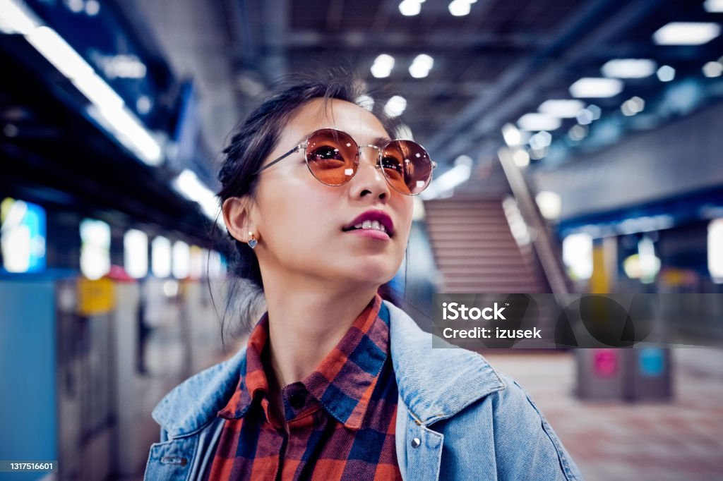 Fashionable woman at subway station Smiling fashionable woman looking away. Young female is at subway station. She is on city break. Passenger Stock Photo