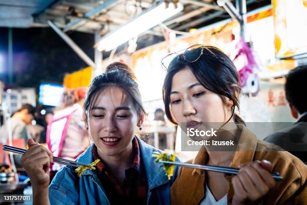 Female Friends Eating Street Food At Night Stock Photo - Download Image Now - 20-24 Years, Adult, Adults Only