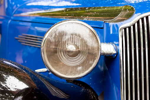 Headlight of vintage blue car, front view, background with copy space, horizontal composition