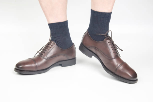 istock Male legs in socks and brown classic shoes on a white background 1317517708