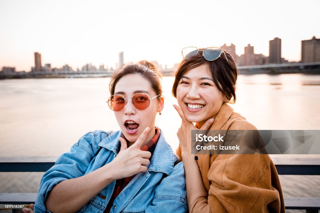 Happy young friends enjoying city break Portrait of cheerful young female friends gesturing. Carefree young women are enjoying city break during weekend. They are wearing casuals. 20-24 Years Stock Photo