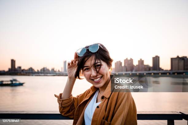 Happy Woman Against River In City During Sunset Stock Photo - Download Image Now - 20-24 Years, Adult, Adults Only
