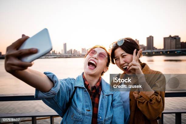 Cheerful Women Taking Selfie During Sunset Stock Photo - Download Image Now - 20-24 Years, Adult, Adults Only