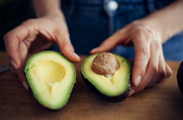 istock Woman Holding Opened Avocado on Cutting Board 1317518616