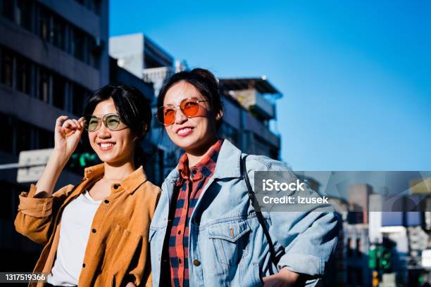 Young Female Friends In City During Sunny Day Stock Photo - Download Image Now - 20-24 Years, Adult, Adults Only