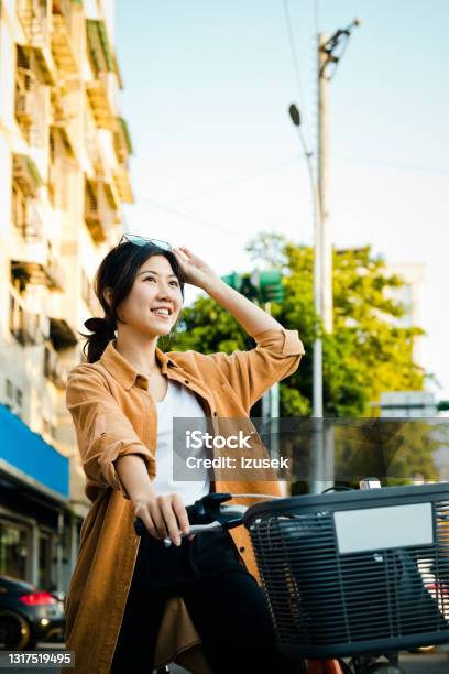 Smiling Young Woman With Bicycle In City Stock Photo - Download Image Now - 20-24 Years, Adult, Adults Only