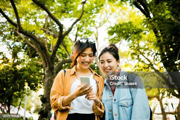 Happy Female Friends In Park During Weekend Stock Photo - Download Image Now - 20-24 Years, Adult, Adults Only