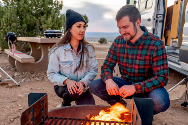 istock Young Multi-Ethnic Couple Out Camping, Warming Themselves By The Campfire, Talking An Enjoying The Evening 1317519600