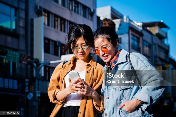 Female Friends Exploring City During Sunny Day Stock Photo - Download Image Now - Smart Phone, 20-24 Years, Adult
