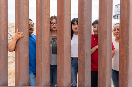 Group of Mexican People looking through the International Border Wall between Chihuahua Mexico and Texas, USA