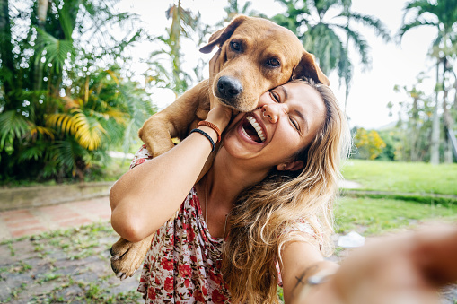 A happy Latin woman enjoys spending time with her dog outdoors in a Viletta countryside home in Colombia.