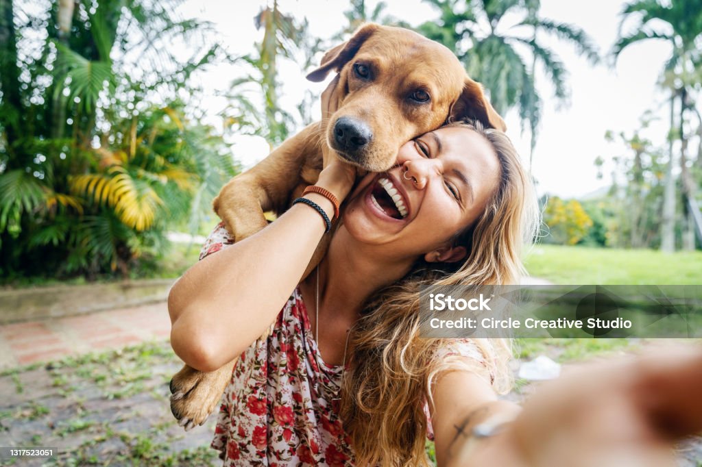 Young Woman Takes Selfie With Her Dog A happy Latin woman enjoys spending time with her dog outdoors in a Viletta countryside home in Colombia. Dog Stock Photo