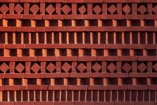 Red brick wall with ornamental pattern in shadow and light gradient