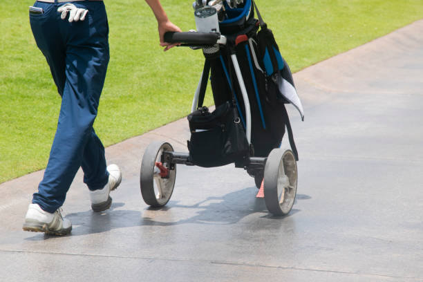 un golfeur marche poussant un sac de golf - golf cart golf bag horizontal outdoors photos et images de collection