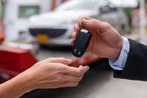 Close-up on a salesman delivering a car while handling the keys - car ownership concepts