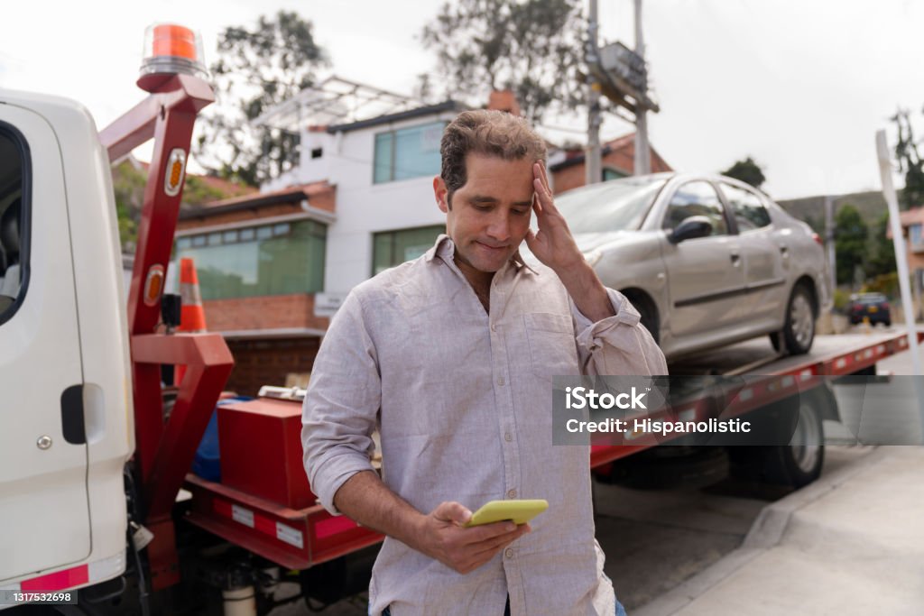 Man having problems with his car and calling roadside assistance Man having problem with his car and calling roadside assistance to take his vehicle to the auto repair shop - roadside assistance concepts Tow Truck Stock Photo