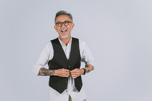asian chinese senior man gray hair with hair stubble rolling up sleeves smiling happily gray background