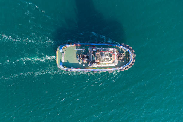 바다 예인선은 항구 물 지역에서 열린 바다로 이동합니다. 헬리콥터에서 사진. 위에서 볼 수 있습니다. - tugboat 뉴스 사진 이미지