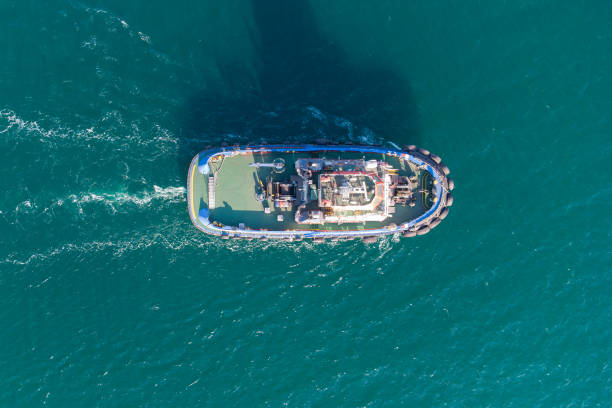 морской буксир перемещается из портовой водной зоны в открытое море. фото с вертолета. вид сверху. - tugboat стоковые фото и изображения