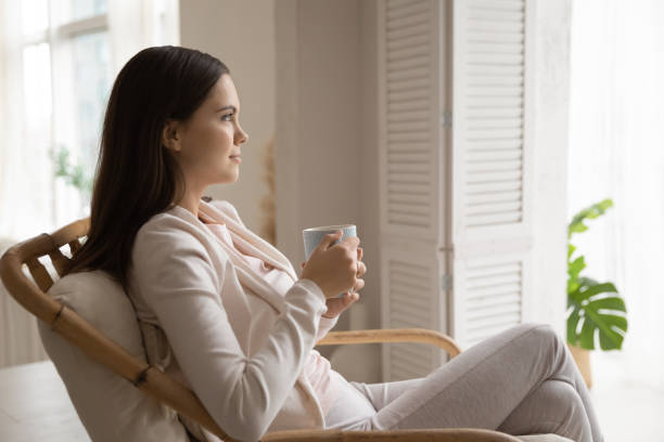 Happy thoughtful girl relaxing at open window