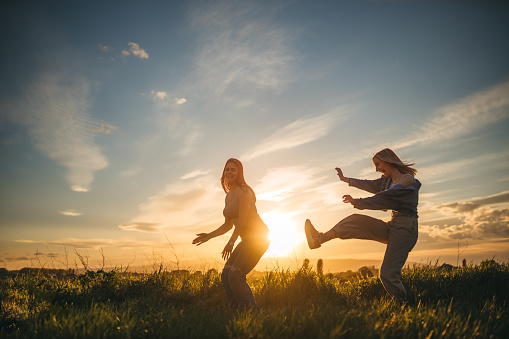 Two girls are jumping happily. In the background is the sunset