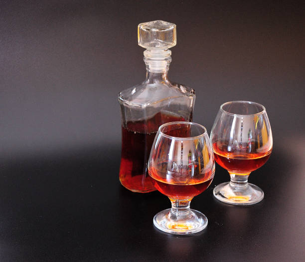 a glass decanter and two glasses of cognac on a black background. - whisky liqueur glass alcohol bottle imagens e fotografias de stock