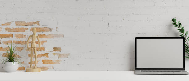 istock Laptop with mock-up screen on white table with decorations and brick wall background, 3D rendering 1317548433