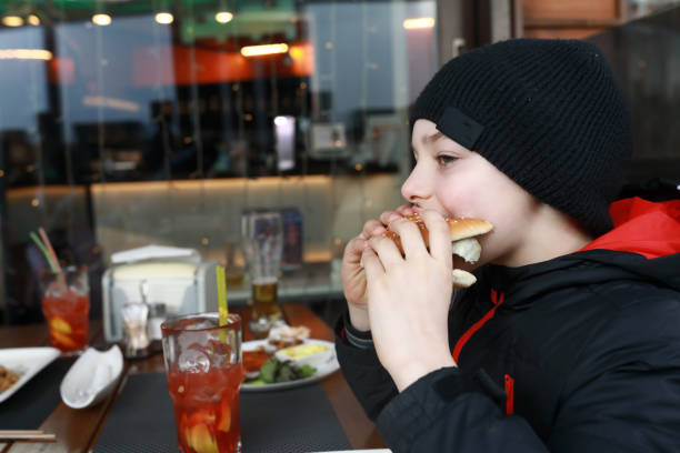 istock Boy eating burger on restaurant terrace 1317551108