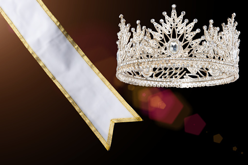 Prize Winning Award for Winner of Miss Beauty Queen Pageant Contest is Sash, Diamond Crown, studio lighting abstract dark draping textile background