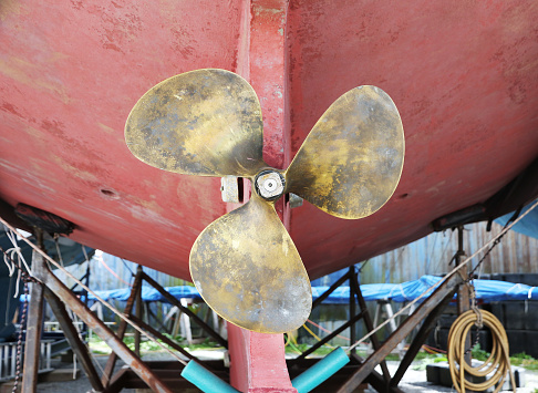 Brass boat propeller on boat hull. Inboard boat engine propeller stock photo.
