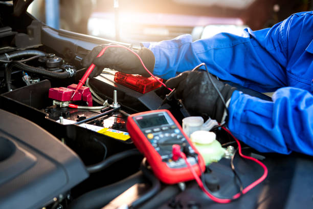 il tecnico utilizza il voltmetro multimetro per controllare il livello di tensione nella batteria dell'auto. batteria dell'auto di assistenza e manutenzione. - car examining mechanic auto mechanic foto e immagini stock