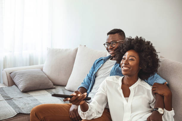 Shot of a happy young couple watching tv together at home. Shot of a happy young couple watching tv together at home. It"s not a cinema but it"s every bit as good. Shot of a couple resting on the couch watching television relaxation lying on back women enjoyment stock pictures, royalty-free photos & images