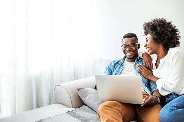 istock Young black couple using laptop sitting on the sofa at home 1317554371
