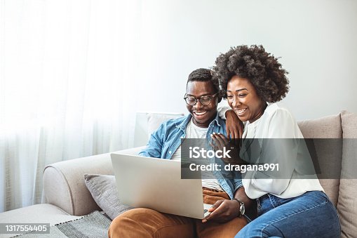 istock Black couple using laptop at home look at each other. 1317554405
