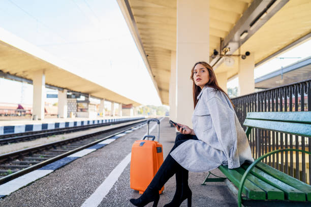 Young woman waiting on station and using smart phone