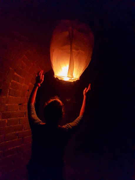 beijing - a woman releasing an air balon next to a brick wall. the balon is slowly drifting away from the man - simatai imagens e fotografias de stock