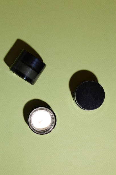istock Opened glass container with cream on a green background 1317556377