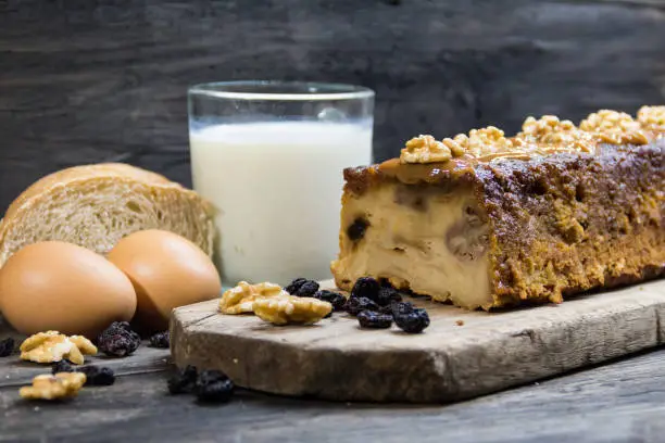 Bread pudding, made with milk, eggs, stale bread and dried fruits on rustic wooden background