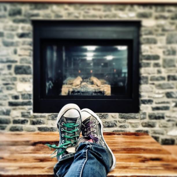 Kicking back in front of a fireplace. Black converse shoes, blue jeans, feet up on a table.